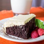 Chocolate Cake with Peanut Butter Icing on a white plate and a glass of milk