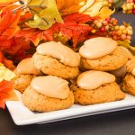 Frosted pumpkin cookies on white plate and fall decorations