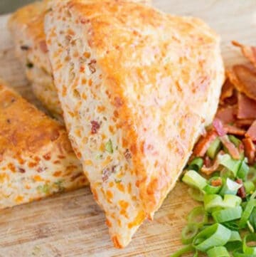Scones on a wooden board with chopped bacon and green onions