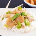 Chicken, cabbage, celery, water chestnuts, and bean sprouts with rice on a white plate with chopsticks