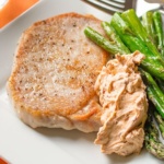Chiptole Brined Pork with cream cheese sauce and asparagus on a plate