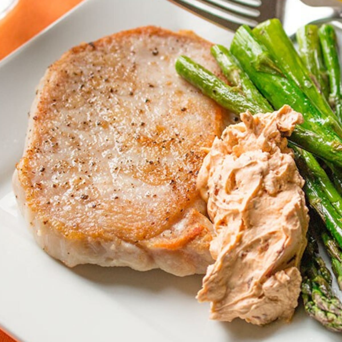 Chiptole Brined Pork with cream cheese sauce and asparagus on a plate
