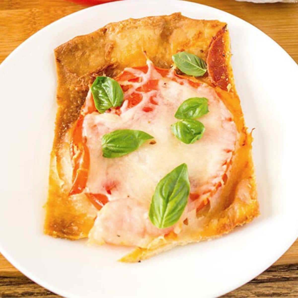 Thin crust pizza slice with tomatoes, basil, and cheese