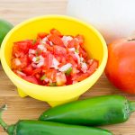 Pico de Gallo in yellow salsa bowl and tomato, lime, onion, and jalapenos