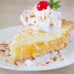 Side View Close-up Pina Colada Pie with Coconut whipped cream, toasted coconut and a cherry on top