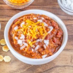 Bowl of Chili topped with onions and cheddar