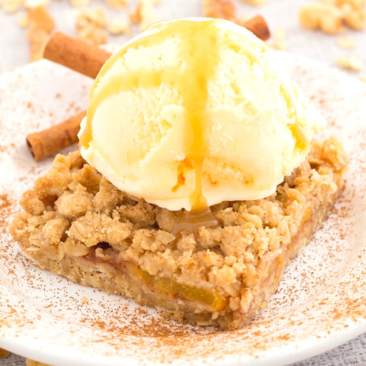 Peach crumble slice topped with ice cream and caramel sauce
