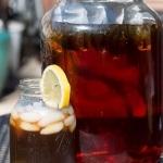 Sun Tea in glass with lemons, ice and sun tea jar