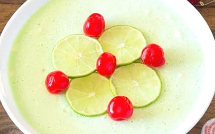 Green Jello Salad in white bowl with limes and cherries