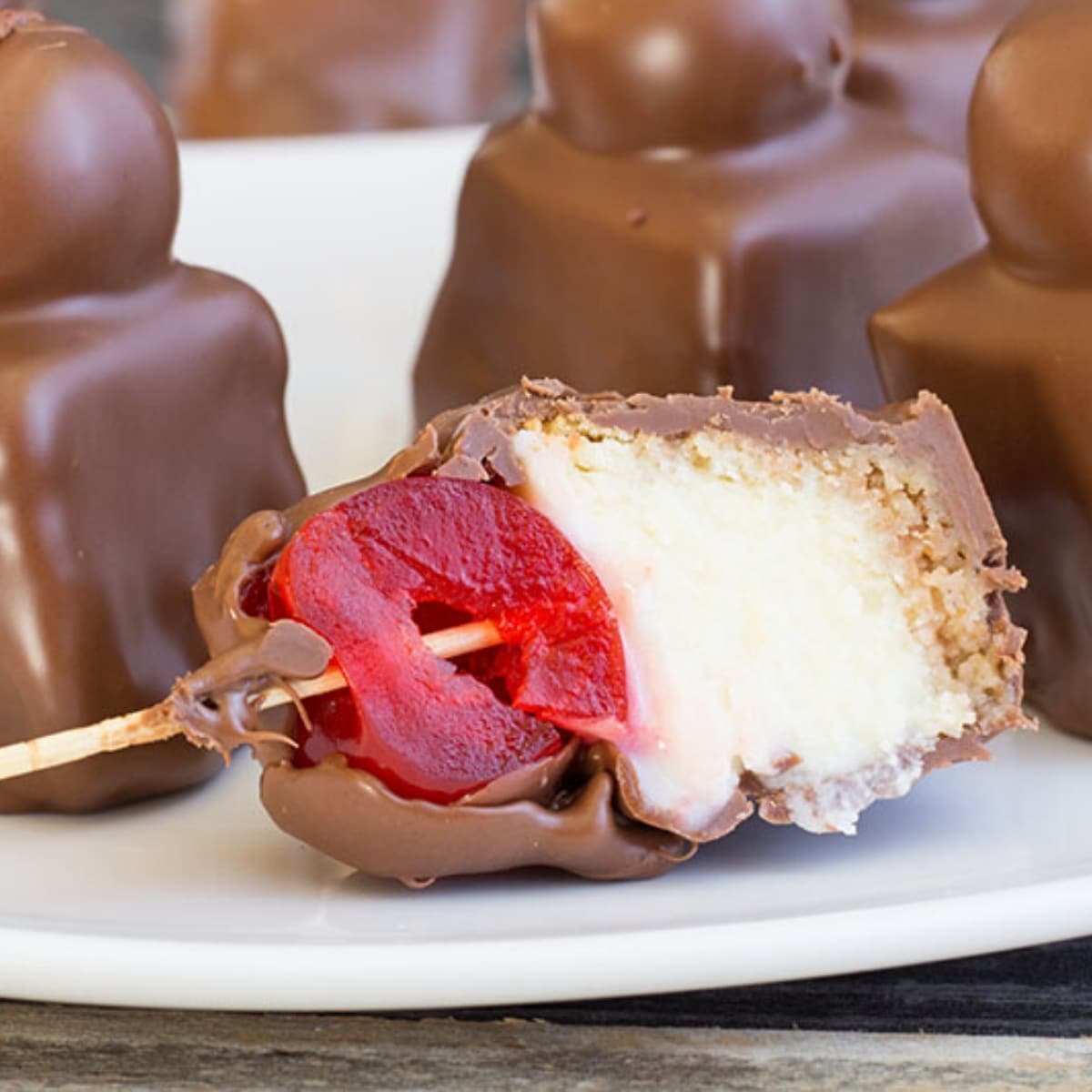 Chocolate covered cheesecake bite with a cherry cut in half