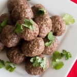 Closeup Indian Spiced Lamb Meatballs on white plate sprinkled with parsley