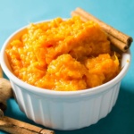 Mashed sweet potatoes in a bowl with cinnamon sticks