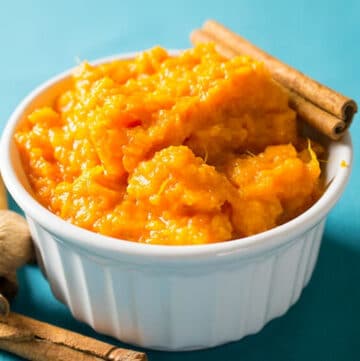 Mashed sweet potatoes in a bowl with cinnamon sticks