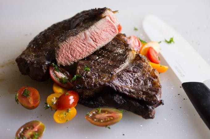 Rare Sous Vide Steak on white plate with tomato pieces