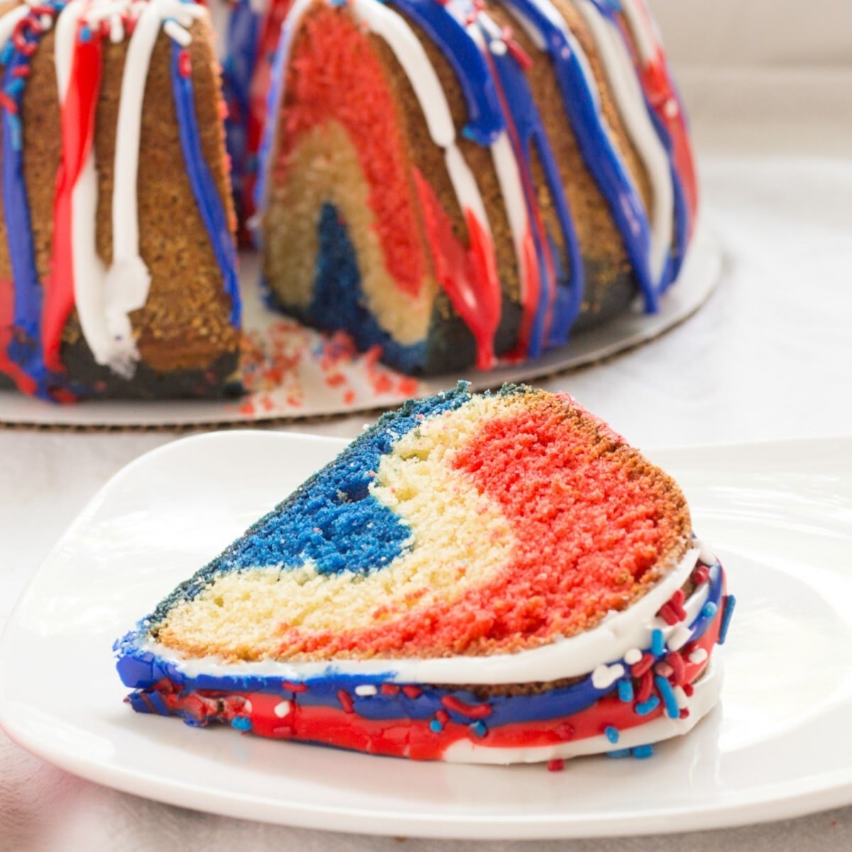 Blue red white and blue pound cake with a cut cake in the background