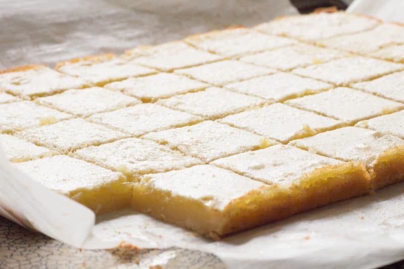 Lemon bars cut into squares on parchment paper