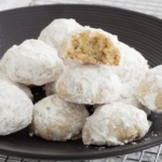 Italian wedding cookies stacked on a black plate