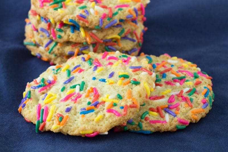 snickerdoodle style cookies covered in colorful jimmies on a blue cloth