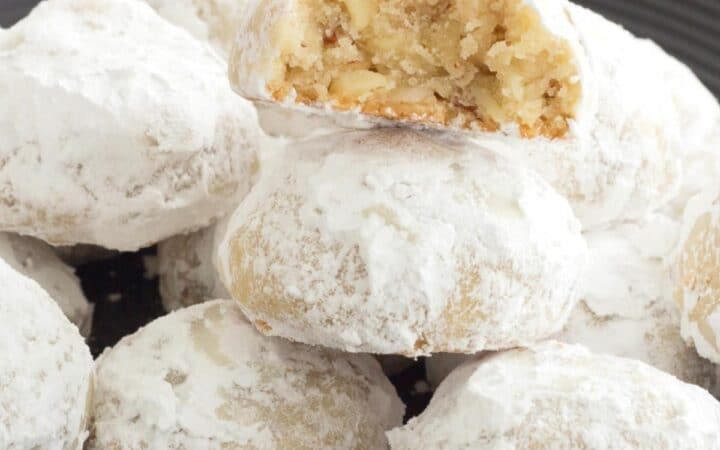 Italian wedding cookies stacked on a black plate