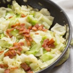 fried cabbage topped with bacon bits in a skillet