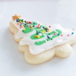 Christmas tree shaped cookie decorated with sprinkles and a candy star on a white plate