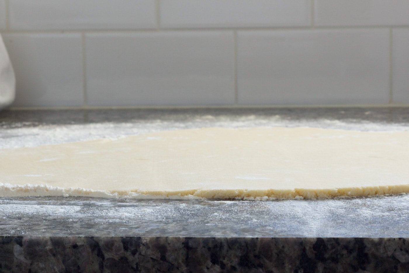 Rolled sugar cookie dough on floured countertop