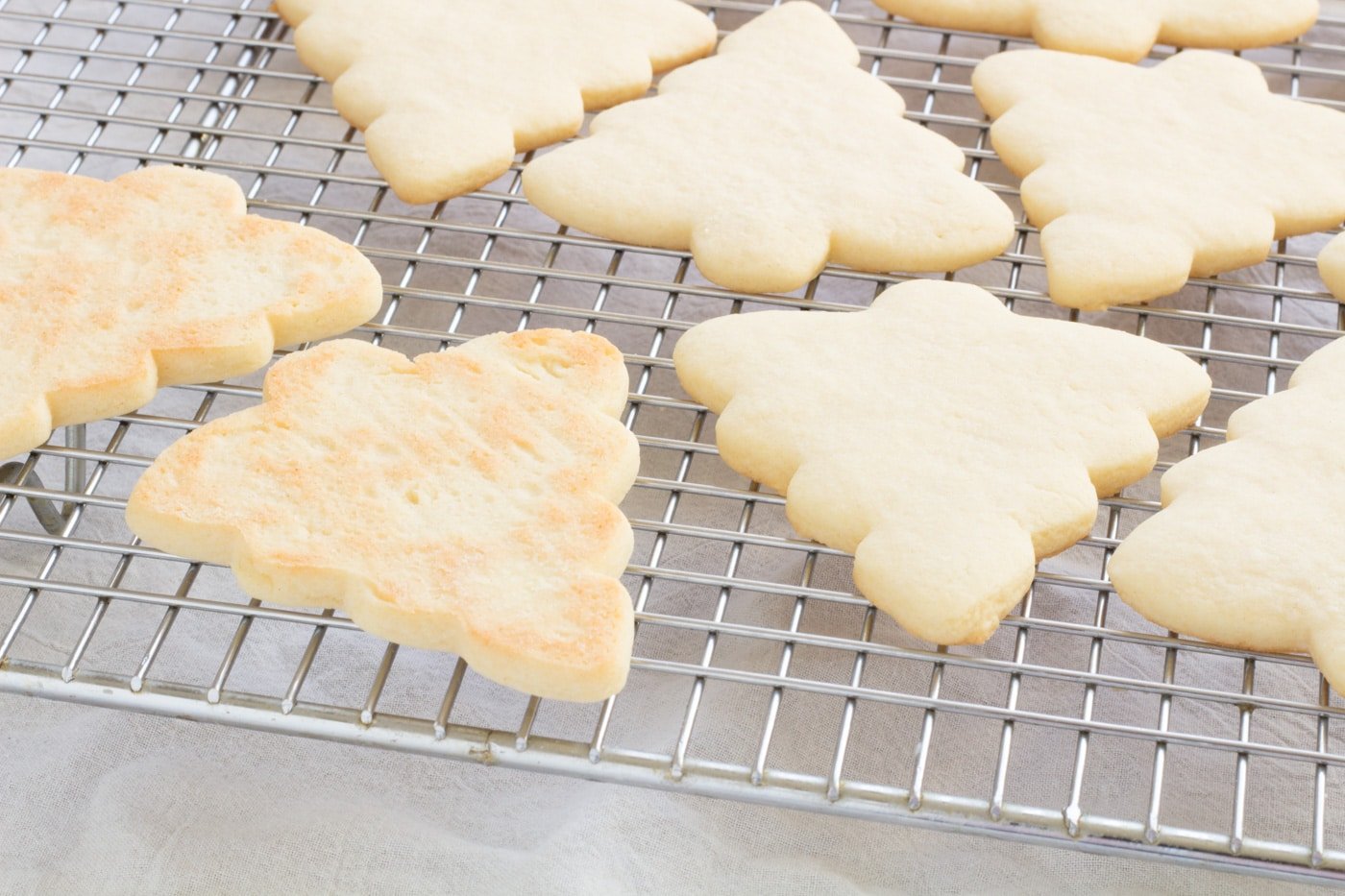 Baked cut out sugar cookies on a cooling rack with bottoms showing on 2 bottom left cookies