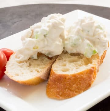 Scoops of chicken salad on sliced crusty bread on a plate
