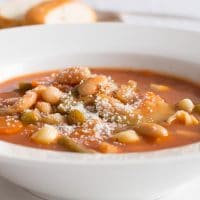 Side view of minestrone soup in a wide rimmed white bowl