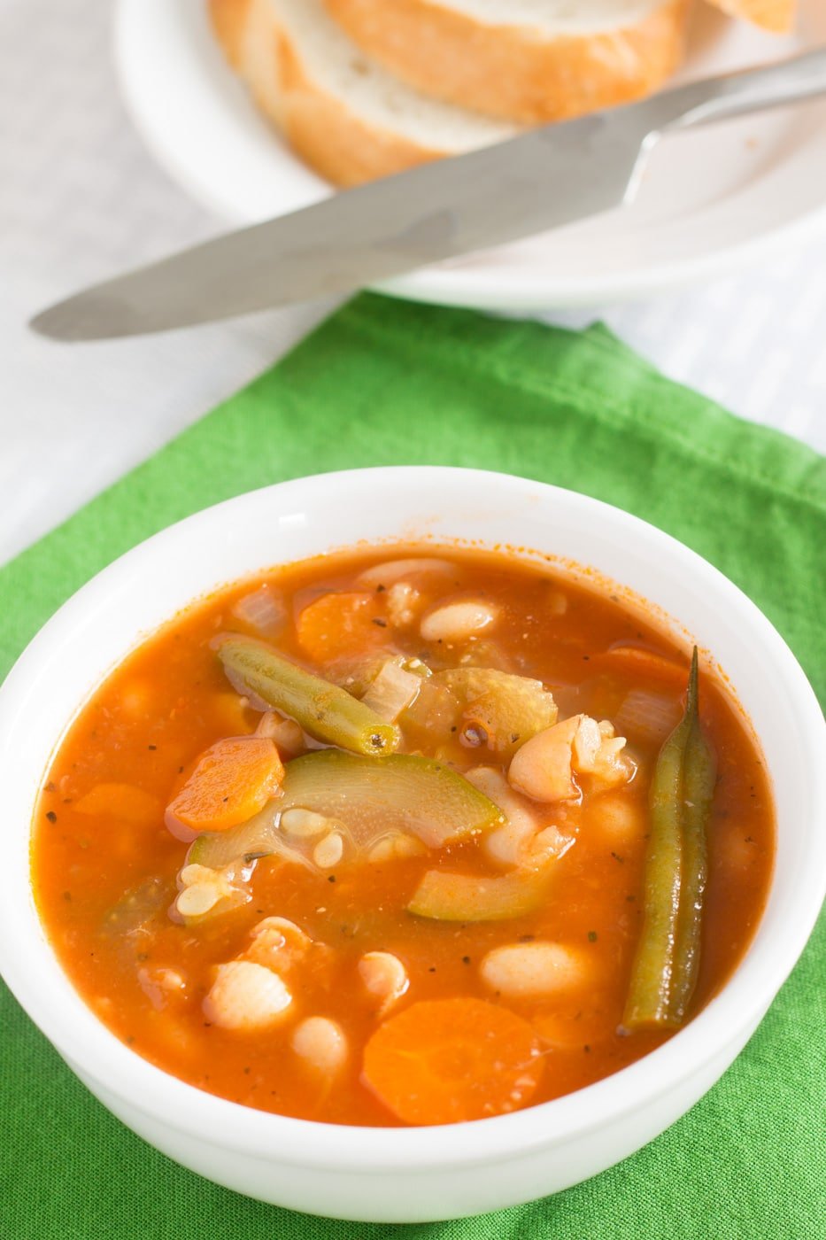 Italian vegetable soup in a white bowl placed on a green napkin