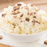 Snickers Apple Salad in a white bowl topped with diced candy