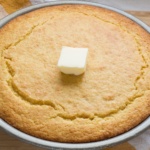 Buttermilk Cornbread topped with a pat of butter in a pie tin