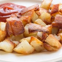 Fried potatoes with ketchup on a white plate
