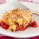 Upclose cherry pineapple dump cake on a plate with red checked napkin
