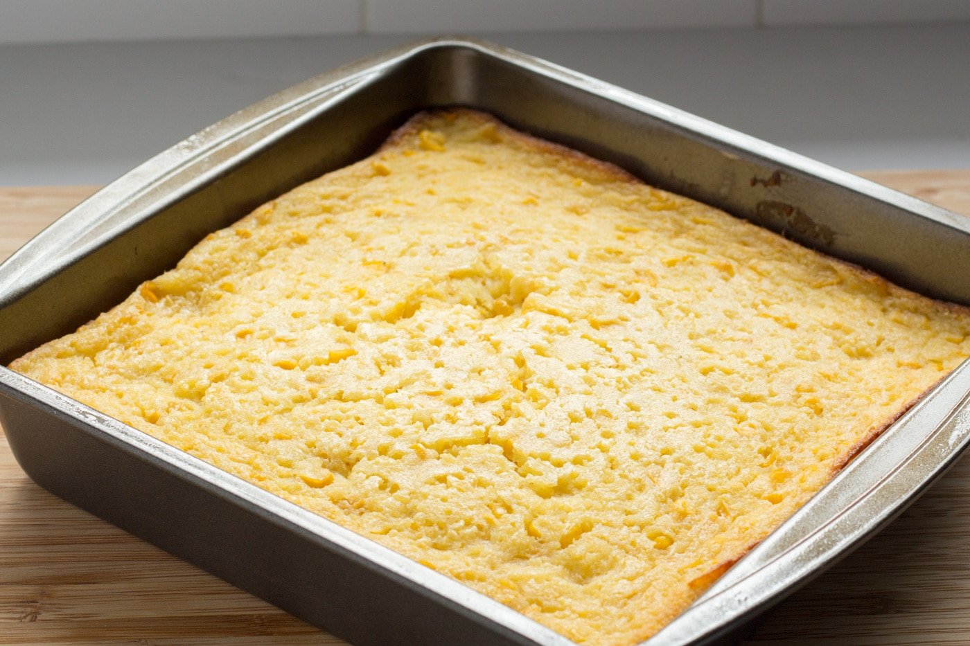 Baked Corn Casserole in a pan on a wooden board