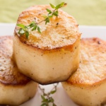 3 Fondant Potatoes and thyme sprigs on a white plate