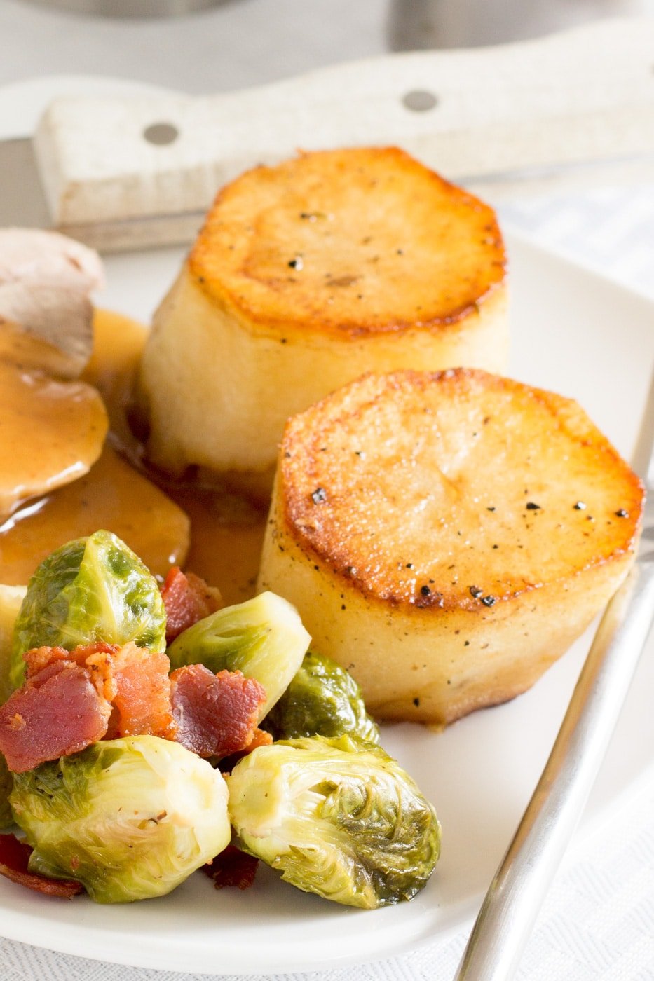 two potato rounds and roasted bacon Brussels sprouts on a white plate