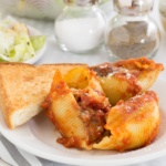 Meat stuffed pasta shells on a white plate with Texas toast
