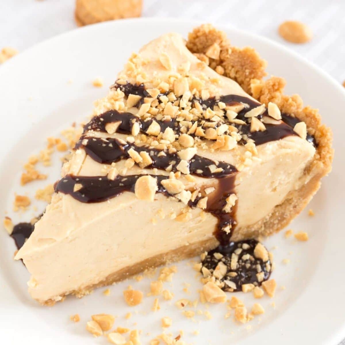 Slice of peanut butter pie topped with chocolate and crushed peanuts
