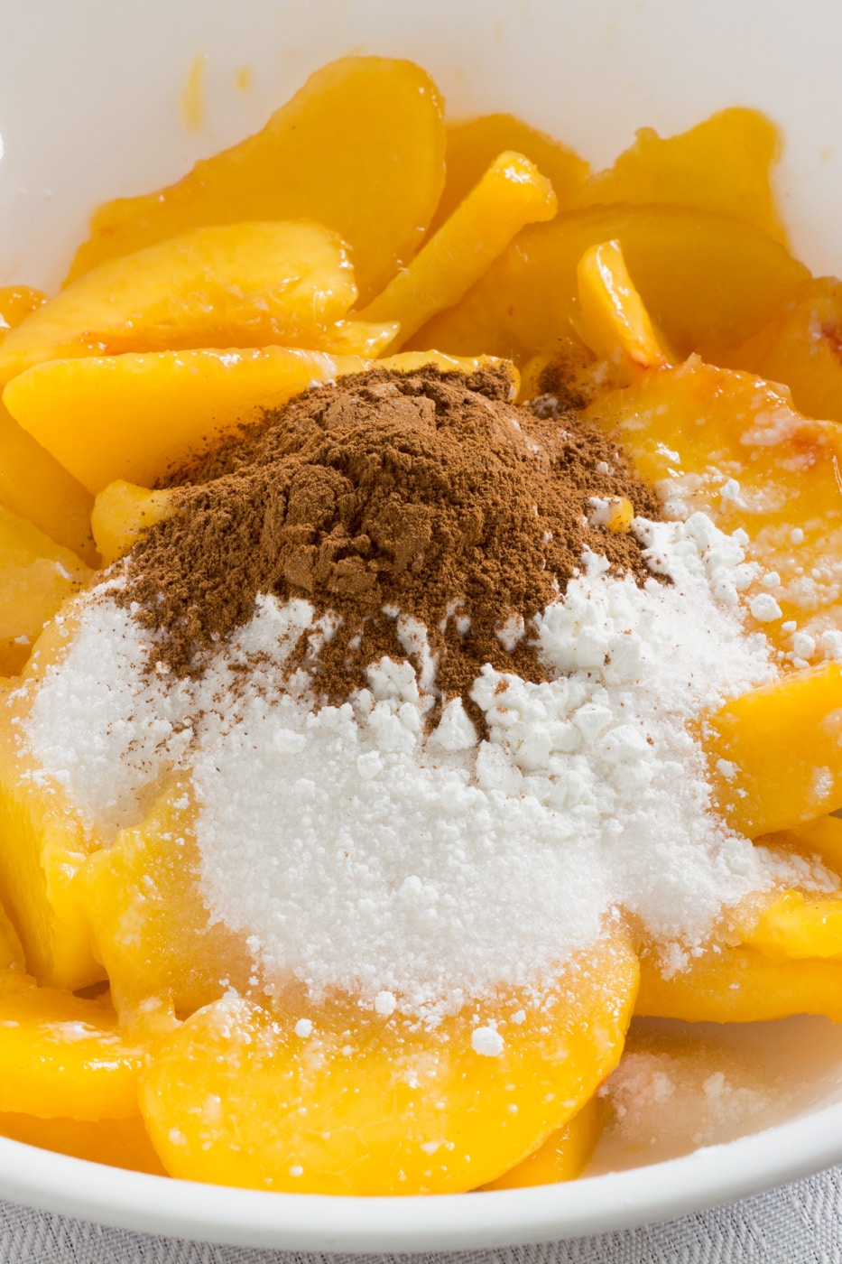 Cinnamon and sugar on top of fresh peaches in a bowl