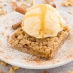 peach bars with ice cream and caramel sauce on a white plate sprinkled with cinnamon