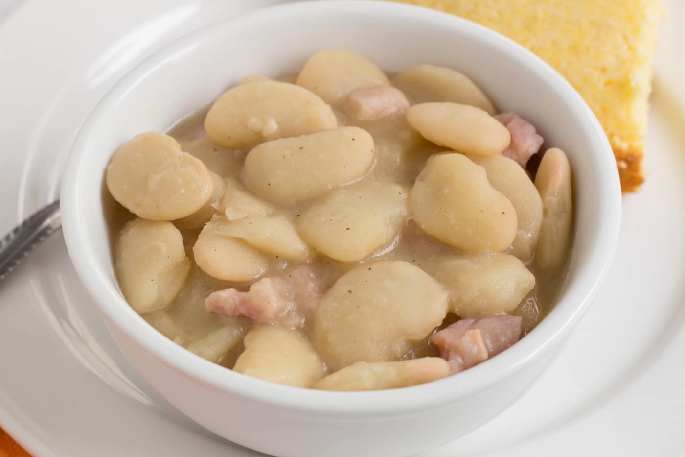 creamy lima beans with ham pieces ina white bowl
