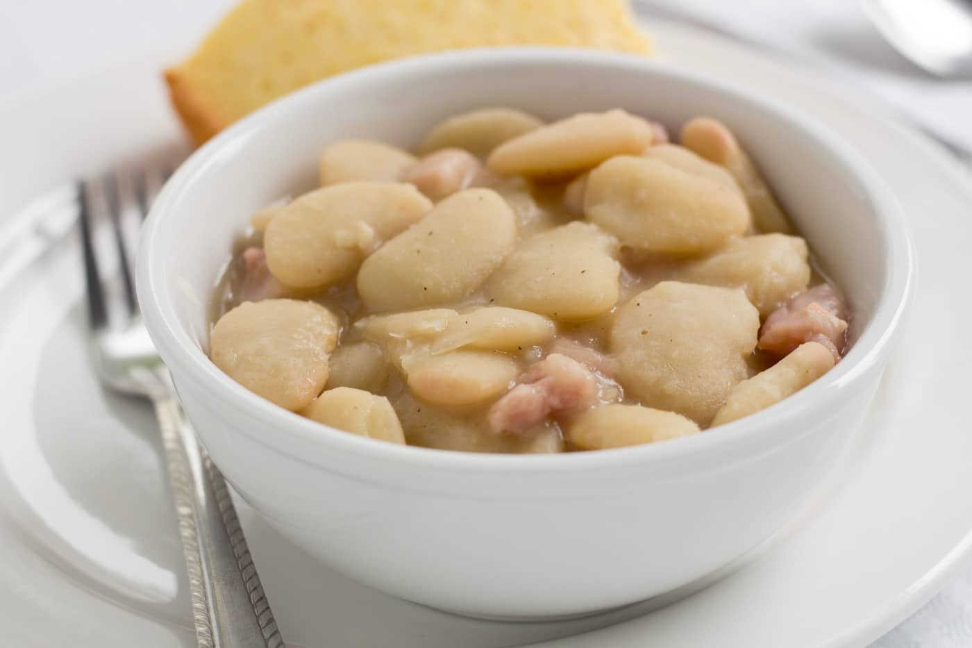 large lima beans with ham in a white bowl