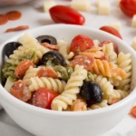 Rotini pasta with black olives tomatoes mozzarella cheese cubes and mini pepperonis in Italian dressing