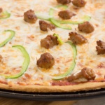 Baked no yeast pizza dough with pizza sauce melted cheese Itlian sausage green peppers and onions
