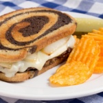 simple patty melt with chips and a pickle on a plate