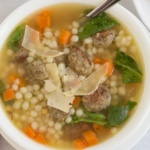 overhead view chicken broth with meatballs pasta balls carrots spinach and shaved parmesan