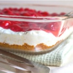 Graham Cracker crust, cream cheese filling, and cherry pie filling layered in a glass dish