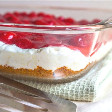 Graham Cracker crust, cream cheese filling, and cherry pie filling layered in a glass dish