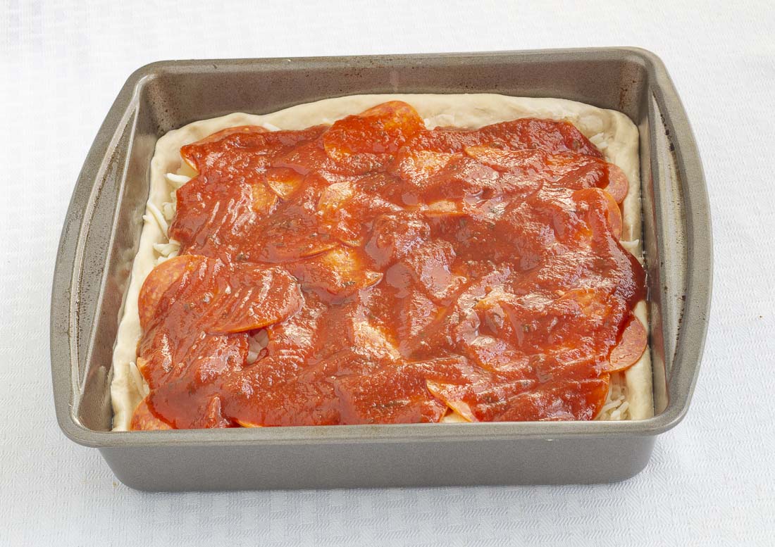 Pizza dough covered with cheese, pepperoni, and sauce